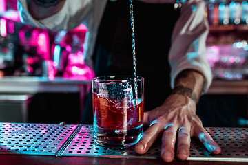 Image showing Expert barman is making cocktail at night club.