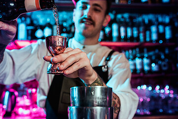 Image showing Expert barman is making cocktail at night club.