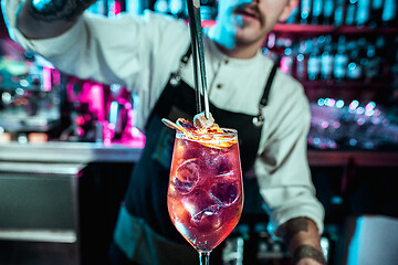 Image showing Expert barman is making cocktail at night club.