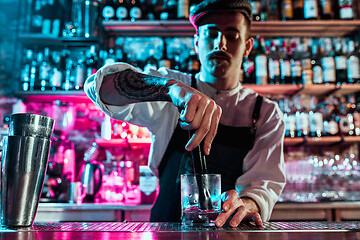 Image showing Expert barman is making cocktail at night club.