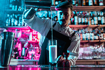 Image showing Expert barman is making cocktail at night club.