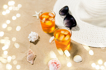 Image showing cocktails, sun hat and sunglasses on beach sand