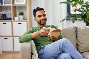 Image showing smiling indian man eating takeaway food at home