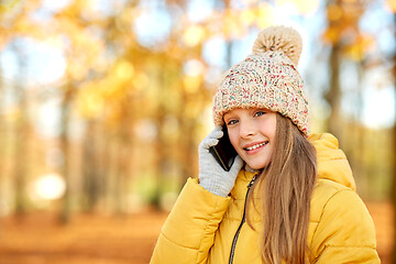 Image showing happy girl calling on smartphone at autumn park