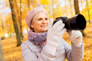 Image showing senior woman with photo camera at autumn park