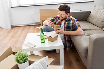 Image showing smiling man eating takeaway food at new home