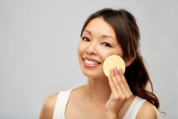 Image showing asian woman cleaning face with exfoliating sponge