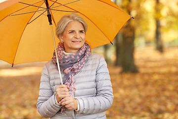 Image showing happy senior woman with umbrella at autumn park