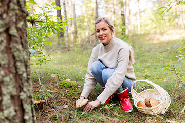 Image showing young woman picking mushrooms in autumn forest