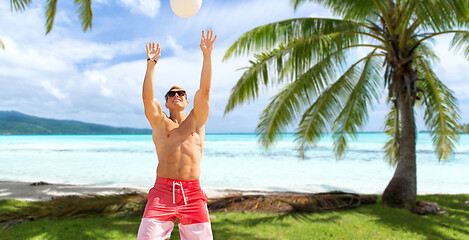 Image showing young man with ball playing volleyball on beach