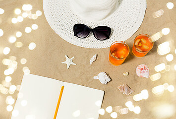 Image showing notebook, cocktails, hat and shades on beach sand