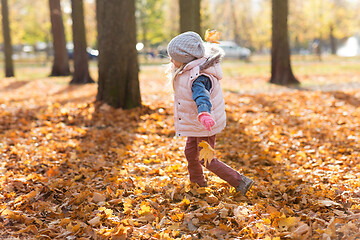 Image showing happy girl playing with leaves at autumn park