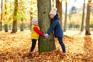 Image showing happy children at tree trunk in autumn park