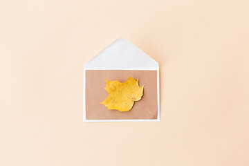 Image showing autumn maple leaf with envelope on beige