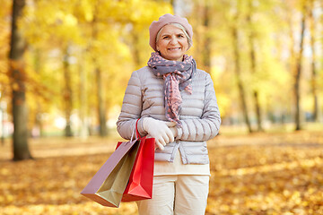 Image showing senior woman with shopping bags at autumn park