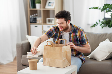 Image showing smiling man unpacking takeaway food at home