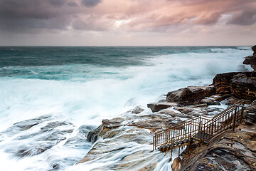 Image showing Large swells engulf the rock shelf  at sunset