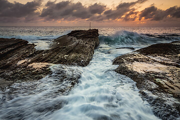 Image showing Waves crash as sunrise dawns over the ocean