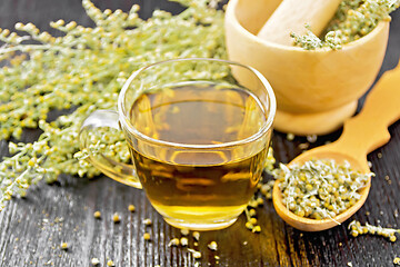 Image showing Tea of gray wormwood in glass cup with mortar on black board