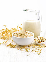 Image showing Flour oat in bowl with milk on wooden board