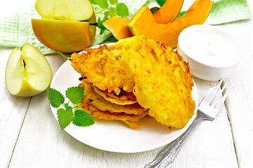 Image showing Pancakes of pumpkin with apple in plate on wooden board