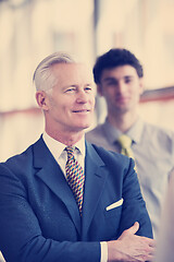 Image showing portrait of senior businessman as leader  with staff in backgrou