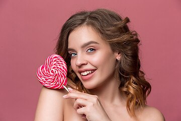 Image showing beauty portrait of a cute girl in act to eat a candy