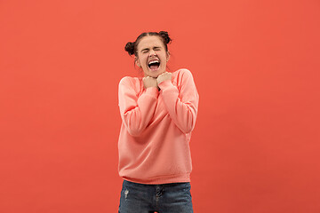 Image showing The happy woman standing and smiling against coral background.