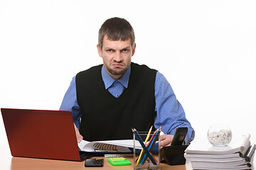 Image showing disgruntled office worker sits in his workplace