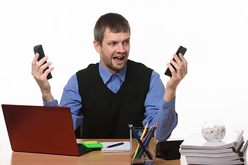 Image showing man with two phones in shock looks at them