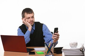 Image showing Office worker dials number on phone sitting at desk