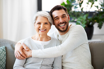 Image showing senior mother with adult son hugging at home