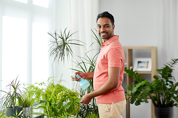 Image showing man spraying houseplant with water at home