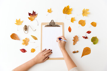 Image showing hands writing on paper on clipboard in autumn