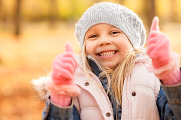 Image showing happy little girl at autumn park showing thumbs up