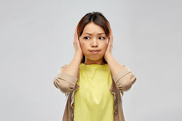 Image showing asian woman closing ears by hands