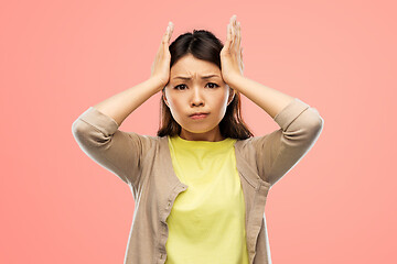 Image showing stressed asian woman holding to her head