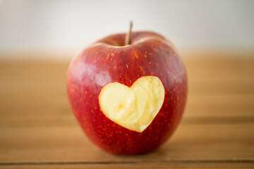 Image showing red apple with carved heart shape on wooden table