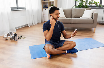 Image showing indian man with smartphone on exercise mat at home