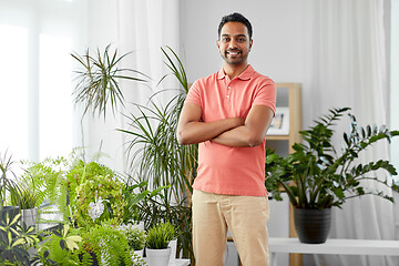 Image showing smiling indian man with houseplants at home