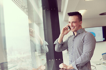 Image showing young business man speaking on  smart phone at office