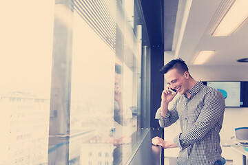 Image showing young business man speaking on  smart phone at office