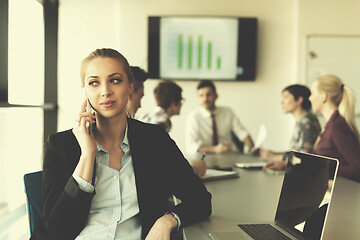 Image showing business woman speeking on phone at office with team on meeting 