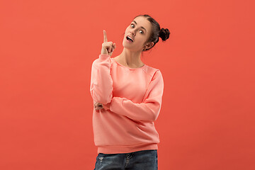 Image showing The happy woman standing and smiling against coral background.