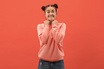 Image showing The happy woman standing and smiling against coral background.