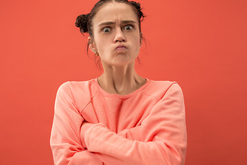 Image showing Portrait of an angry woman looking at camera isolated on a coral background