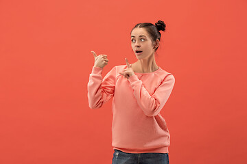 Image showing The happy woman standing and smiling against coral background.