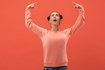 Image showing The happy woman standing and smiling against coral background.