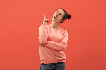 Image showing The happy woman standing and smiling against coral background.