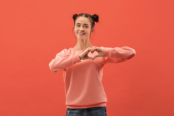 Image showing Portrait of attractive cute girl with bright makeup with love isolated over coral background